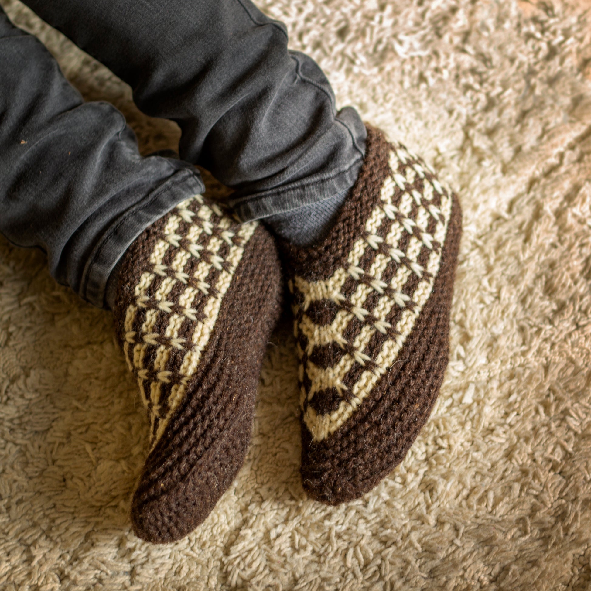 Knitted wool slippers on feet on a carpet background