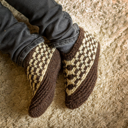 Knitted wool slippers on feet on a carpet background